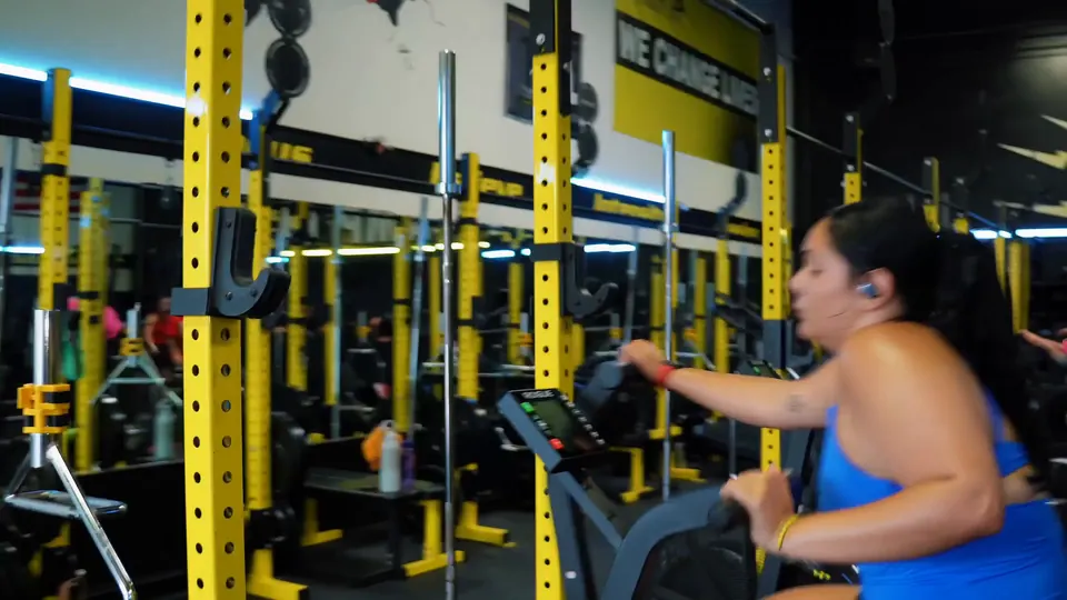 A member on the bike beside the yellow squat racks