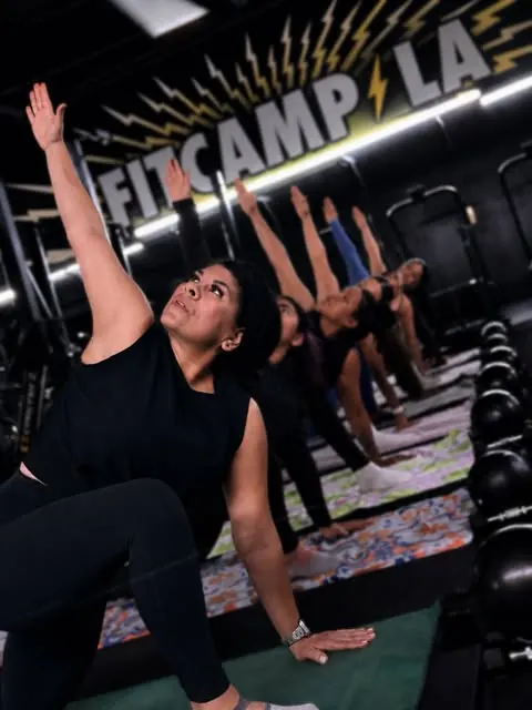 A Mat Pilates class stretching under the Fit Camp LA sign